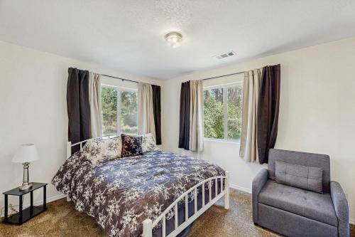 a bedroom with a bed and a chair and windows at 1 Mi to Boat Launch! Lake-View Chiloquin Retreat in Chiloquin