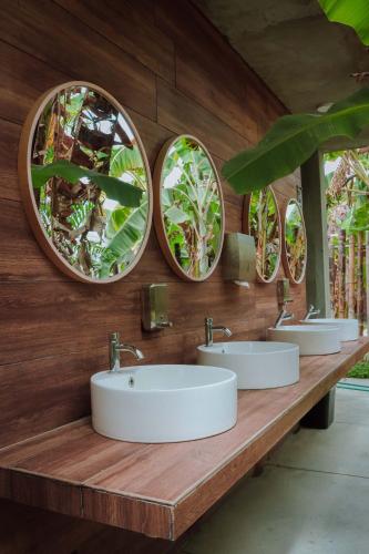 a bathroom with three sinks and three mirrors at Bungalows Spilberg in Colán