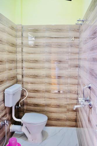 a bathroom with a toilet and a wooden wall at Sky View Guest House in Shānti Niketan