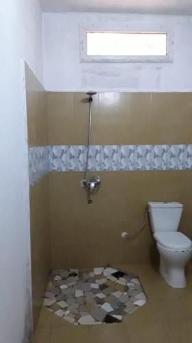 a bathroom with a toilet and a window at Chambre simple à louer in Fatick