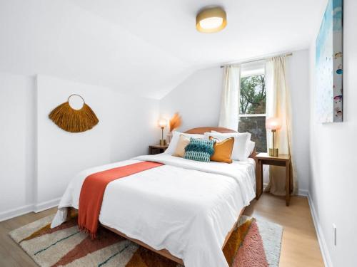 a white bedroom with a bed with orange and blue pillows at Hot Tub 5 Mins from Cedar Point Modern Updates in Sandusky