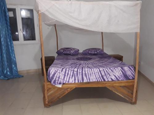 a wooden bed with a canopy in a room at KEUR MAMY DOUSSOU à Ndangane campement in Ndangane
