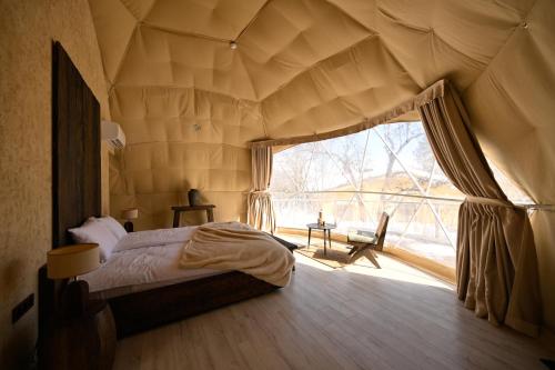 a bedroom with a bed and a large window at Anima Resort Aghveran - Forest Retreat in Aghveran