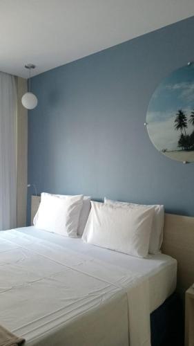 a bedroom with a white bed with a blue wall at Flat colado a praia de Boa Viagem in Recife