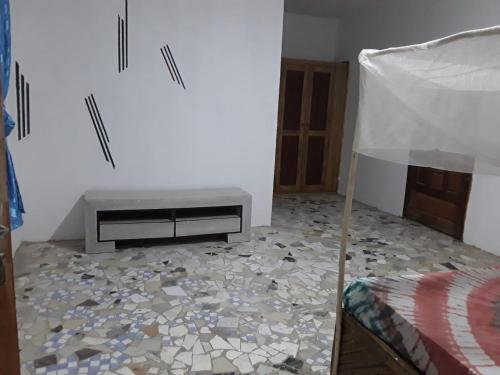 a room with a bed and a table on a floor at Chambre climatisée balcon in Fatick