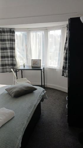 a bedroom with a bed and a table with a laptop at Zoran home 3 in Leicester