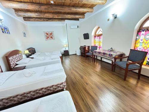 a room with two beds and a table and chairs at SHoxtut INN 18-19Th Century in Bukhara