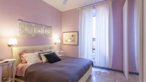 een slaapkamer met een bed met paarse muren en een raam bij Rental in Rome Otranto Relax in Rome
