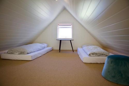 two beds in a small room with a window at FjordNest Cabin in Hvannasund