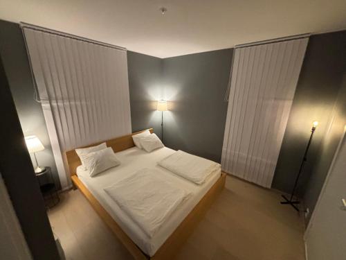 a small bedroom with a bed with white sheets and pillows at Apartment in Central Røa Oslo by the Train Station in Oslo