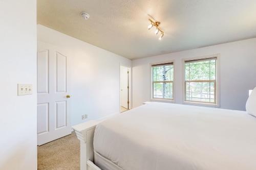 a white bedroom with a bed and two windows at Hike, Golf & Explore: Driggs Home w/ Patio & Grill in Driggs