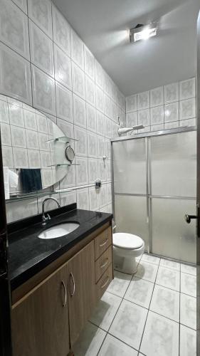 a bathroom with a toilet and a sink and a shower at Casa com piscina 20 Leitos in Cuiabá