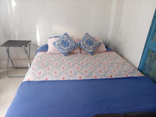 a bed with blue and pink pillows on it at Santorini house y Santorini house 2 in San Pedro de Atacama