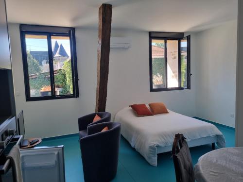 a room with a bed and a chair and windows at L'éveil à la nature in Limoges