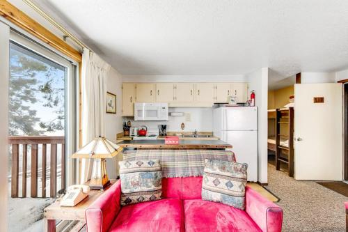 a living room with a pink couch and a kitchen at Mountain Condo Ski Access & Sunset Deck in Boise
