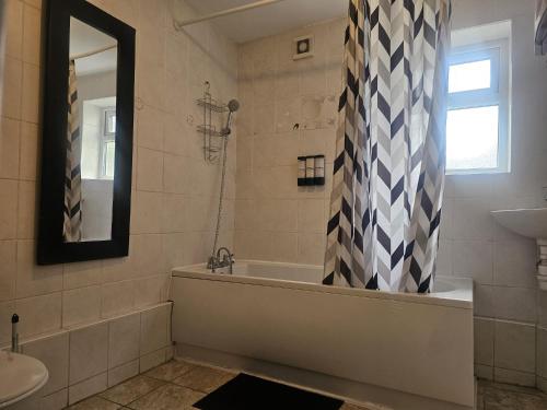 a bathroom with a tub and a sink and a mirror at Seraphic Homes Medway Kent in Gillingham