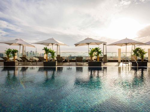 a pool with tables and umbrellas on a building at The Canvas Dubai - MGallery Hotel Collection in Dubai