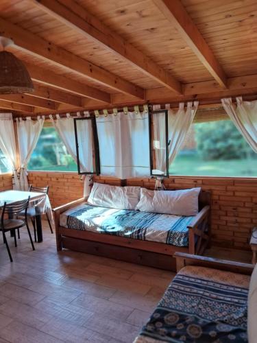 a bedroom with a bed and a table and windows at El Druida 3 in Villa General Belgrano