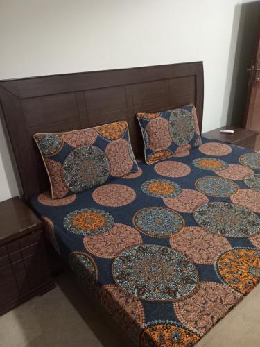 a bed with a quilt and pillows on it at The Velmora G-13 in Islamabad