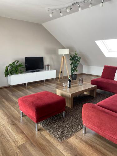 ein Wohnzimmer mit zwei roten Sesseln und einem Fernseher in der Unterkunft Ferienwohnung Eich in Kelberg