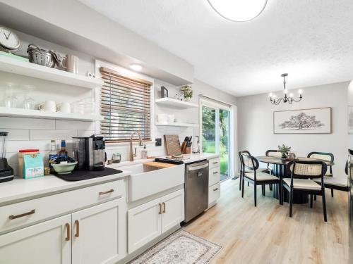 a kitchen with white cabinets and a table with chairs at Beautiful Ranch with Outdoor Patio and Room for 6 in Munroe Falls