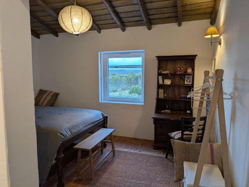 a bedroom with a bed and a desk and a window at Herdade dos Calvinos, Monte 2 - Alandroal in Parreiras