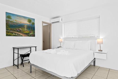 a bedroom with a white bed and a painting on the wall at Private Studio w Pool Patio steps to the Beach in Deerfield Beach