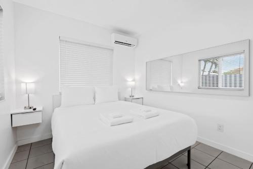 a white bedroom with a white bed and a window at Private modern studio w pool - Steps to the beach in Deerfield Beach