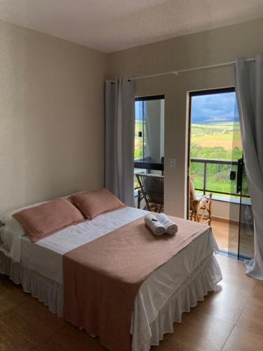 a bedroom with a bed and a balcony with a view at Casa Portal Carrancas in Carrancas
