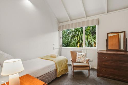 a bedroom with a bed and a chair and a window at Waitati Retreat in Waitati