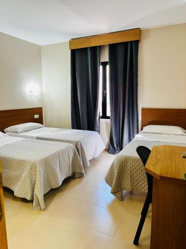 a bedroom with two beds and a table and a window at Hostal Costabella in Fuengirola