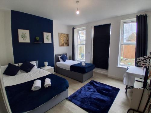 a bedroom with two beds and a blue wall at Central Bedford FREE Parking & Private Garden& Conservatory Perfect for large group of people in Bedford
