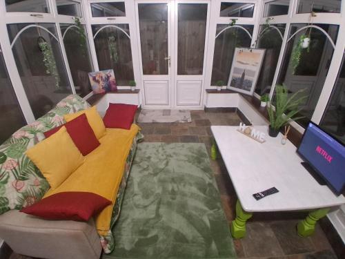 a living room with a couch and a table at Central Bedford FREE Parking & Private Garden& Conservatory Perfect for large group of people in Bedford