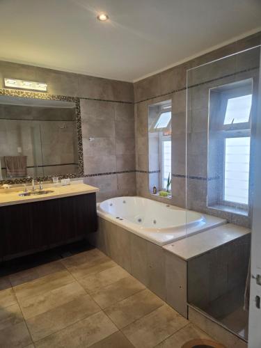 a bathroom with a tub and a sink and a mirror at Espectacular Casa con pileta y jacuzzi in San Juan