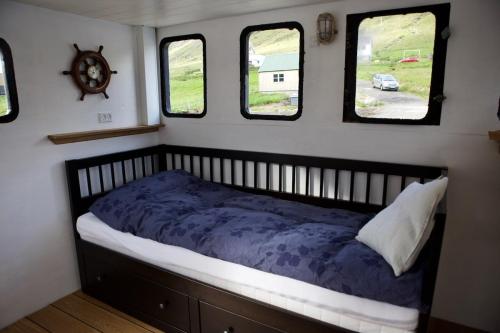 a bed in a small room with three windows at Captains Room - Havborg in Hvannasund
