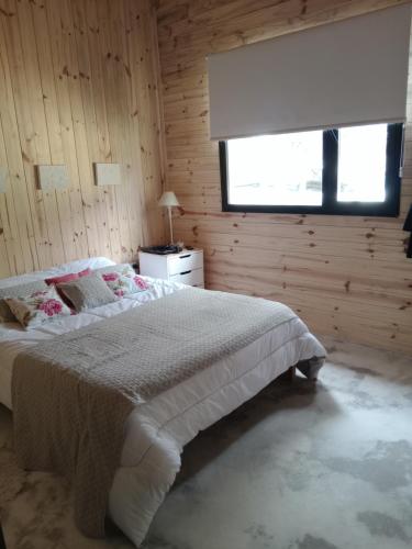 a bedroom with a large bed and a window at Cabañas La Mansa, Casa grande in Balcarce