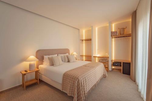 een slaapkamer met een groot wit bed met witte kussens bij Authentic Tavira Hotel in Tavira