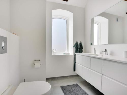 a white bathroom with a toilet and a sink at Two-Story Loft with Large Terrace in Løkken