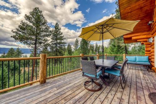 a table and chairs on a deck with an umbrella at Cascade Lakeview Log Cabin in Cascade