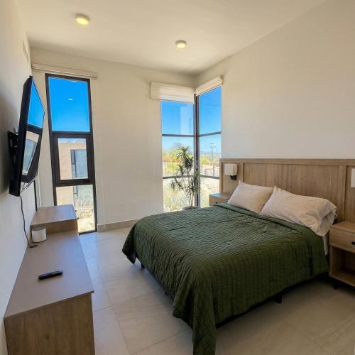 a bedroom with a bed and a tv and windows at Kocoy Oceanfront condo in Punta Peninsula in Bahía Kino