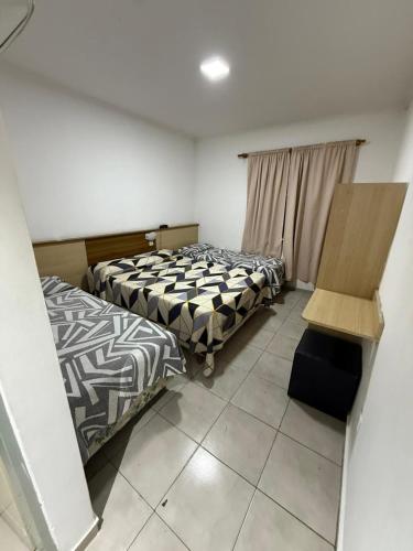 a bedroom with two beds and a chair in it at HOTEL DIAMANTE in Resistencia