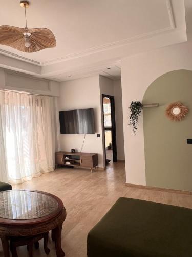 a living room with a table and a flat screen tv at Central Urban Terrace in Rabat