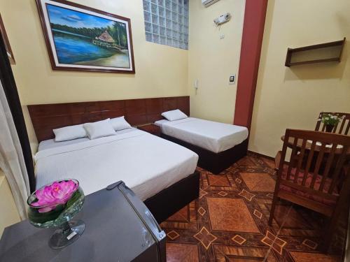 a bedroom with two beds and a table with a vase of flowers at Alojamiento El Cardenal in Iquitos