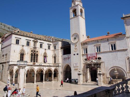 a large building with a clock tower in a courtyard at Miró Studio Apartments Dubrovnik in Dubrovnik