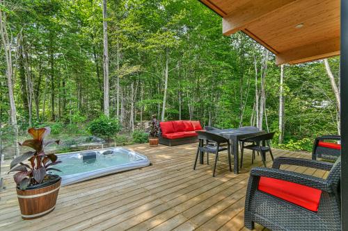 eine Terrasse mit Whirlpool, Tisch und Stühlen in der Unterkunft Chic & Bois in La Conception