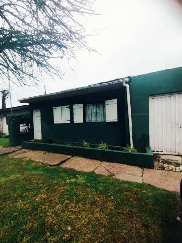 a green house with white windows and a yard at Martin House in Chascomús