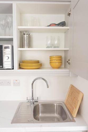 a kitchen sink with plates and glasses on shelves at Derry City Centre 1 & 2 Bedroom Modern Apartments in Derry Londonderry