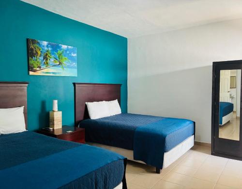 a bedroom with two beds and a blue wall at Hotel Palmeras Los Cabos in Cabo San Lucas