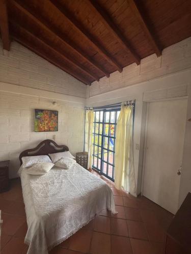 a bedroom with a bed and a large window at Finca Cercanías Marinilla - Casa Campestre in Marinilla