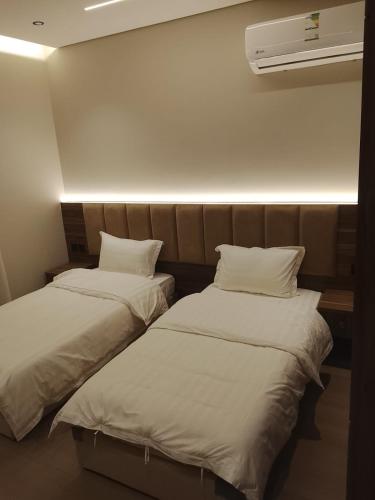 two beds sitting next to each other in a room at شقة واحة رتيل الفندقية in Al-ʿUla